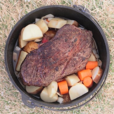 Looking down into a Dutch oven with a searedpot roasted piece of beef serounded with vegetables.