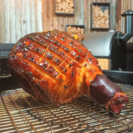 Ham fully cooked sitting on the smoker before it is pulled off