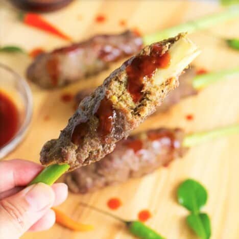 A partially eaten lemongrass beef skewer drizzled with barbecue sauce.