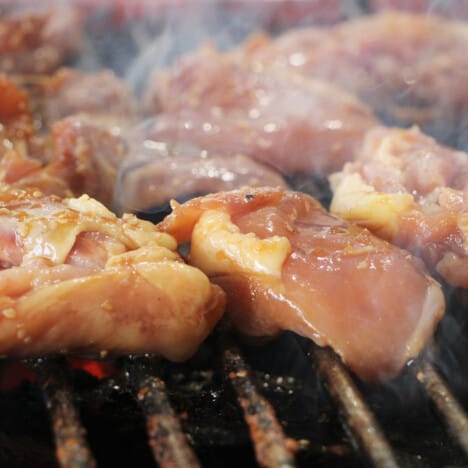 Raw chicken placed on a grill rack to cook.