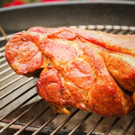 A piece of smoked pork butt sits on a grill grate.