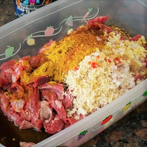 A plastic container holding the sliced beef, lemongrass, curry, and other marinade ingredients.