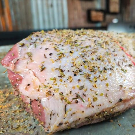 A raw boned leg of lamb covered with a seasoning herb rub.