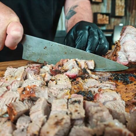 Chopped lamb with more lamb being cut with a knife in the background.