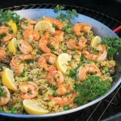 A paella pan filled with a colorful shrimp paella garnished with parsely.