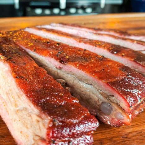 Close up of cut ribs on a wooden chopping board.