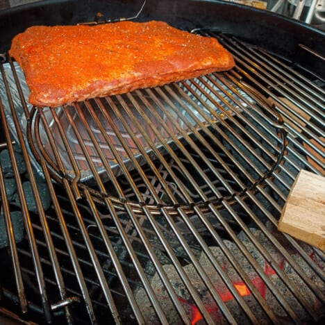 Ribs cooking in a kettle grill using an indirect cooking method.