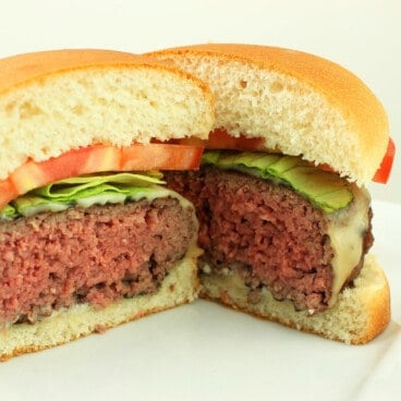 A hamburger cut in half revealing a medium-rare interior.