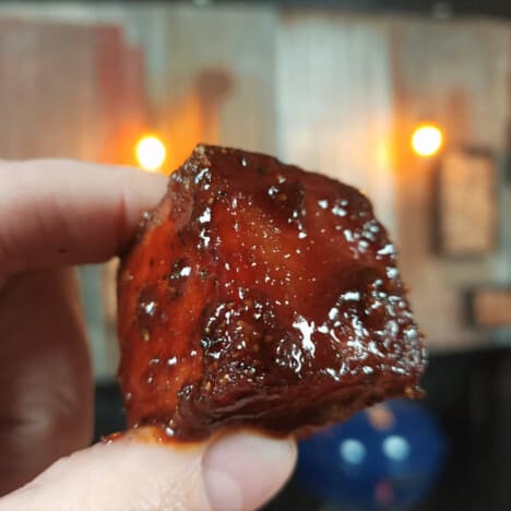 Holding a spam burnt end between a thumb and forefinger.