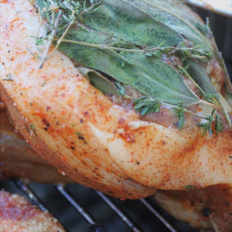 A raw pork steak with a sausage stuffing and fresh sage and thyme.