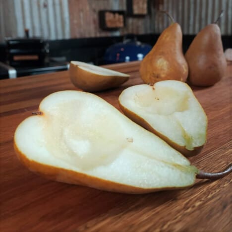 A pear cut in half with whole pears in the background.