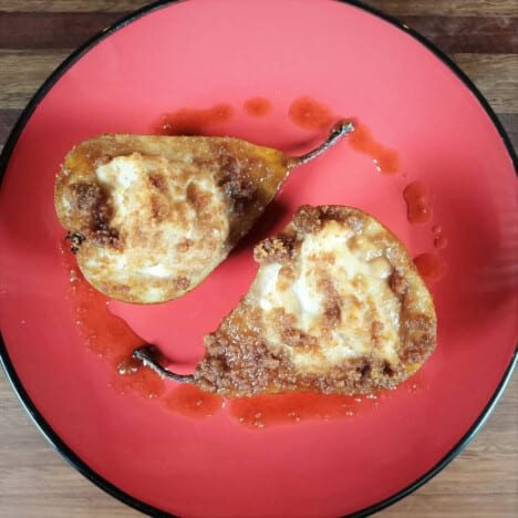 A serving of two half stuffed pears on a read plate.