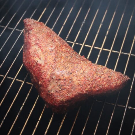 A cooked tri-tip sitting on a grate in a smoker.