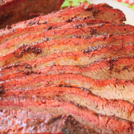 Rows of sliced brisket with a red-hued crust.