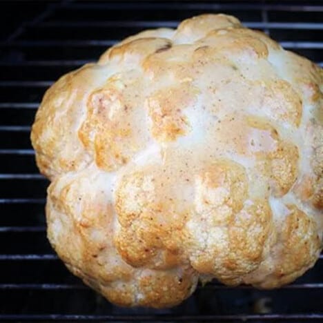 A cauliflower on the grill with a golden brown covering.