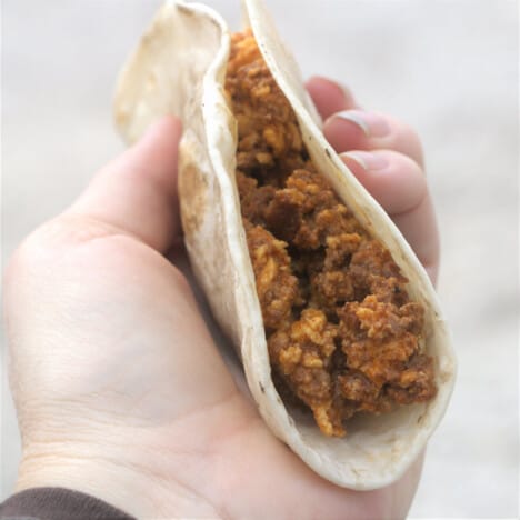A chorizo egg taco being held ready to eat.