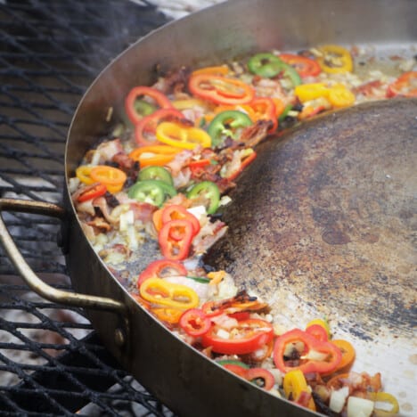 The edge of the discada simmering brightly colored bell peppers over a campfire.