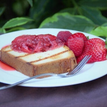 Side view of grilled pound cak topped with stewed and fresh berries.